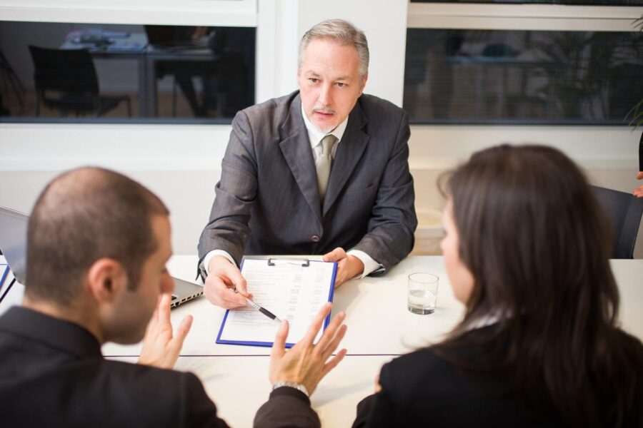 A professional lawyer seated at a desk, counseling a couple during a divorce consultation, symbolizing legal guidance and support